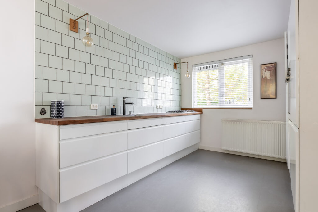 Modern kitchen with white cabinets and tiled wall.