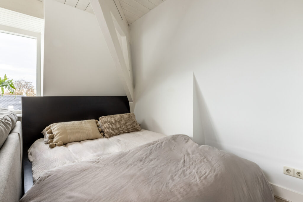 Cozy bedroom with cushions and white walls.
