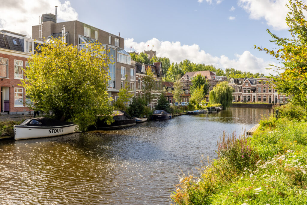 Scenic canal with boats and houses, sunny day.