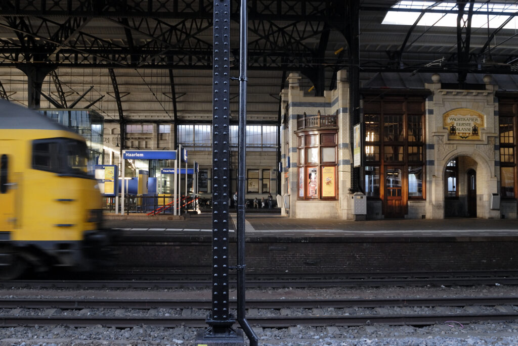 Yellow train passing Haarlem station platform