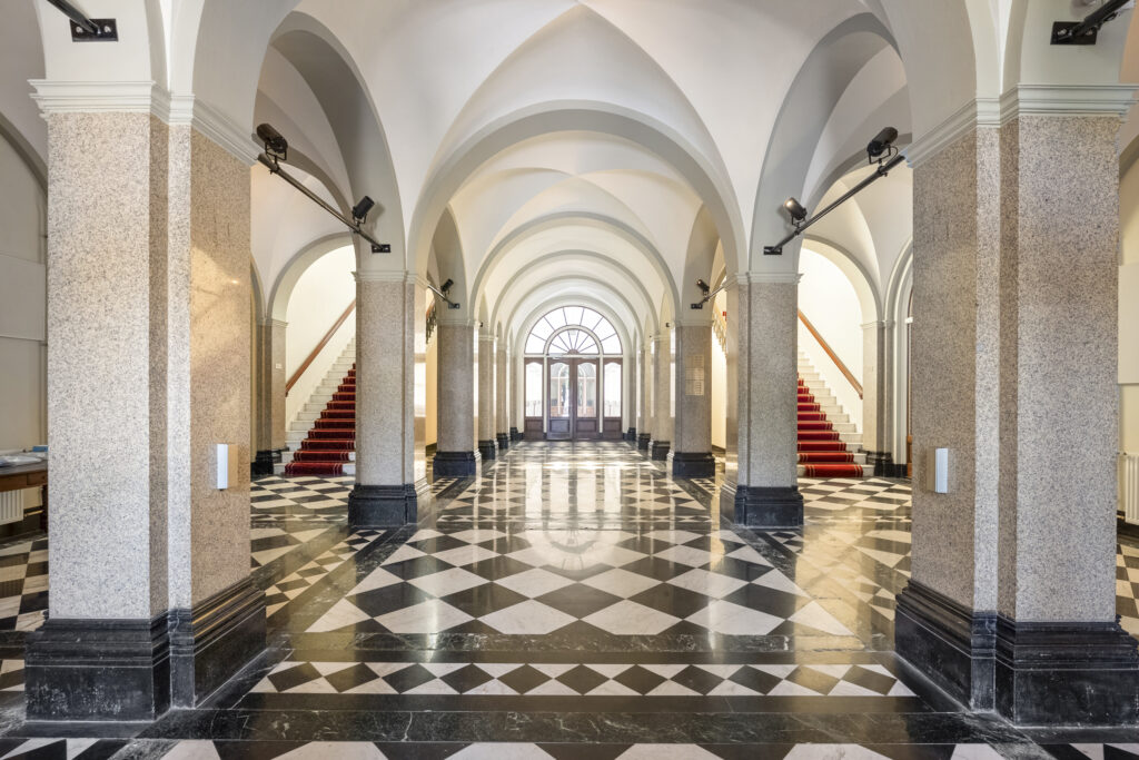 Elegant grand hall with arches and checkered floor.