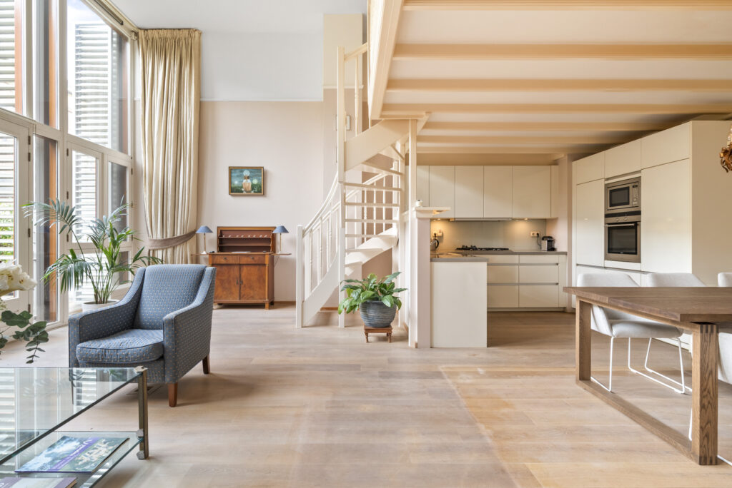 Spacious modern living room with staircase and kitchen.