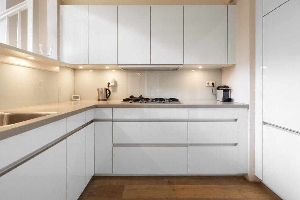 Modern white kitchen with appliances and wooden floor.