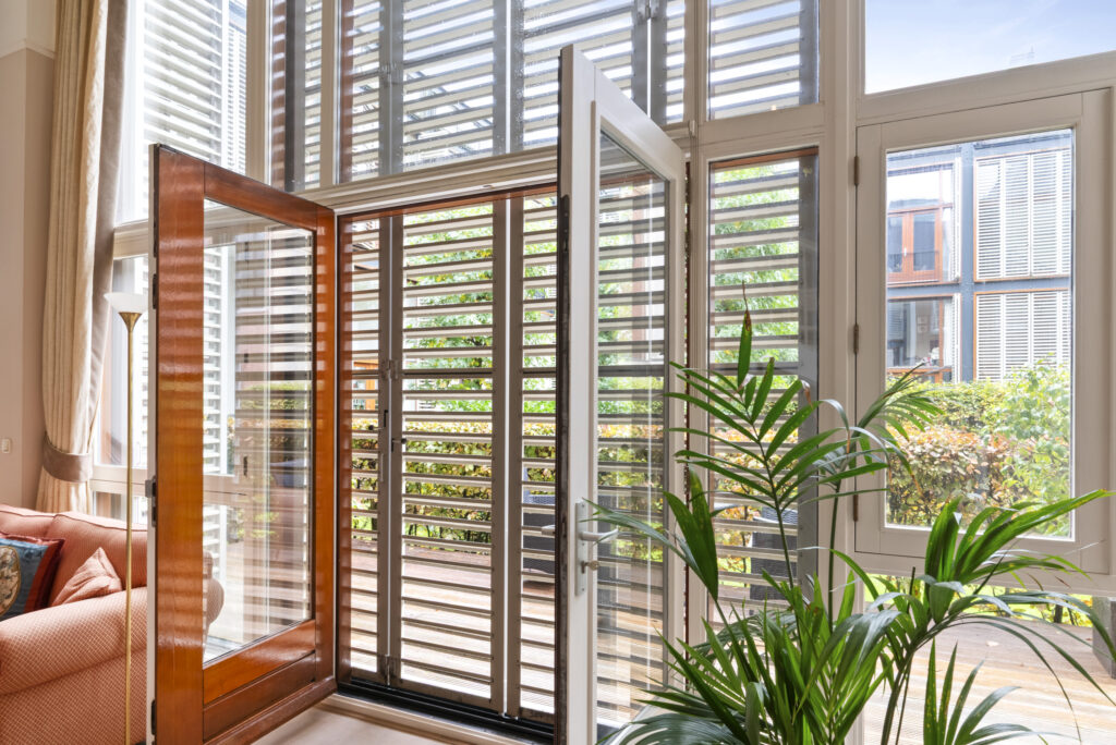 Sunlit room with open glass doors and plants.