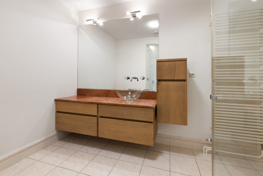 Modern bathroom with wooden vanity and glass sink.