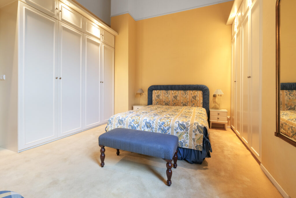Cozy bedroom with floral bedspread and white cabinets.