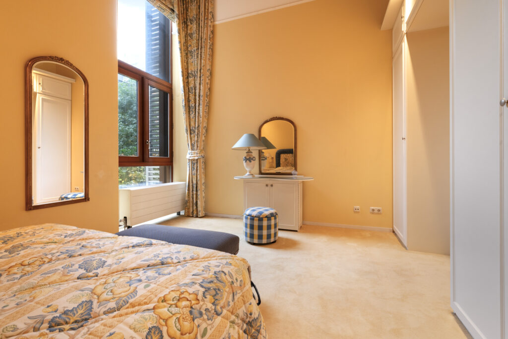 Cozy bedroom with elegant decor and large windows.