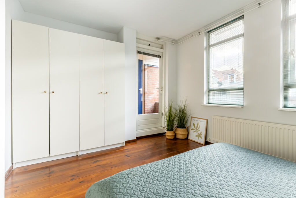 Minimalist bedroom with large windows and wooden floor.