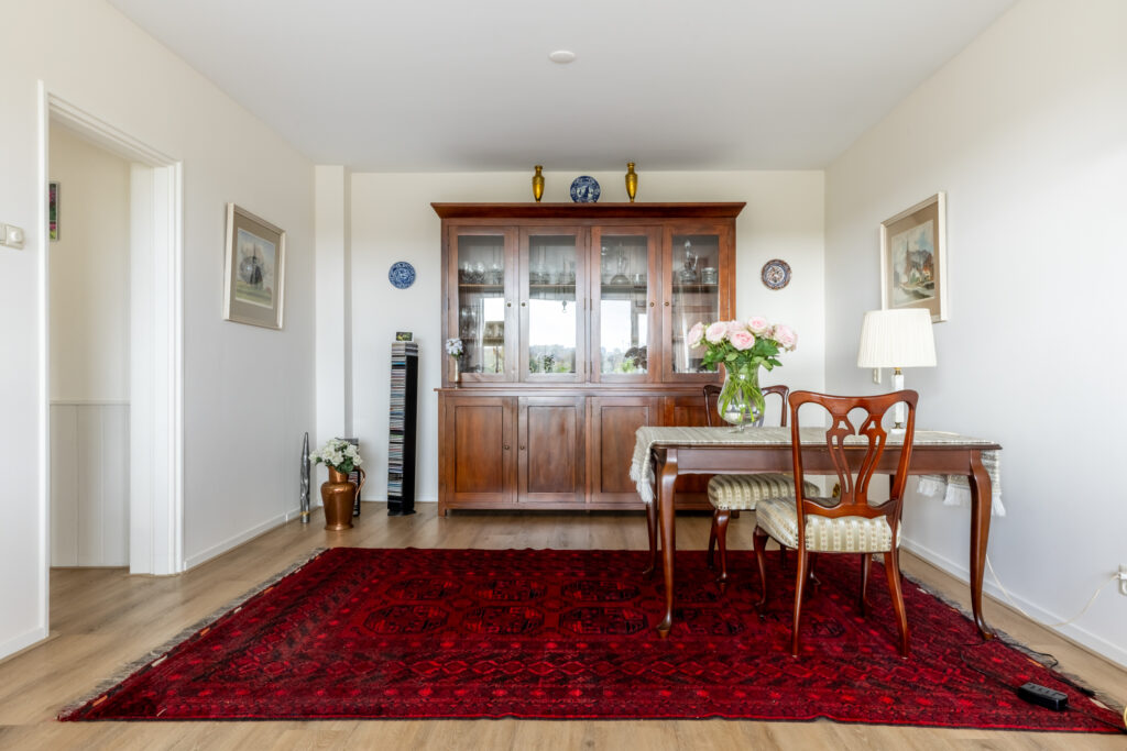 Elegant dining room with wooden furniture and red rug.