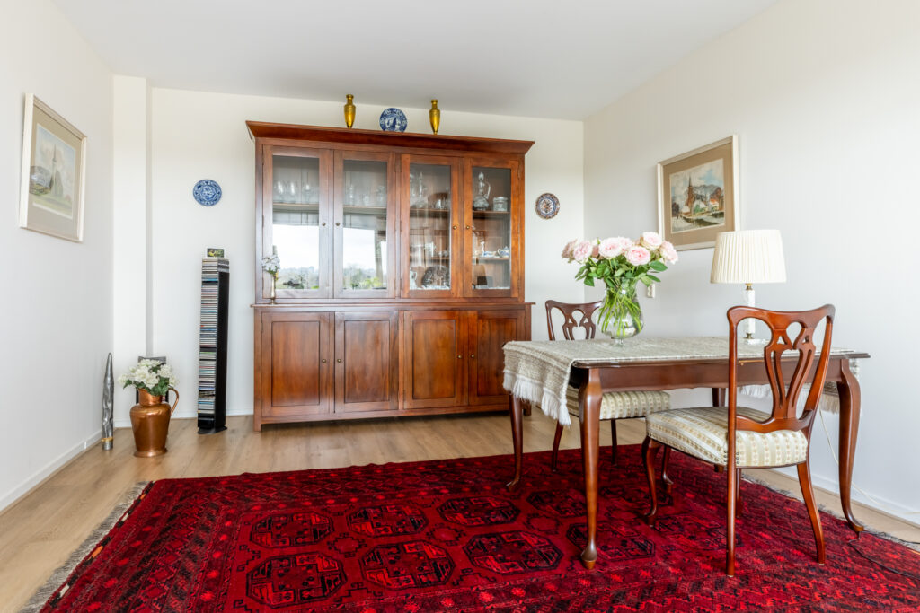 Elegant dining room with wooden furniture and red rug.