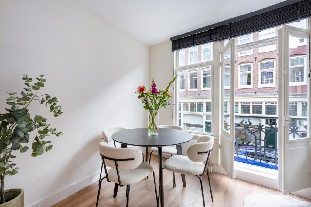 Bright dining area with round table and flowers.