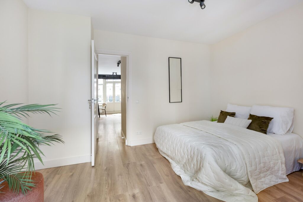 Modern bedroom with white bed and wooden floor.