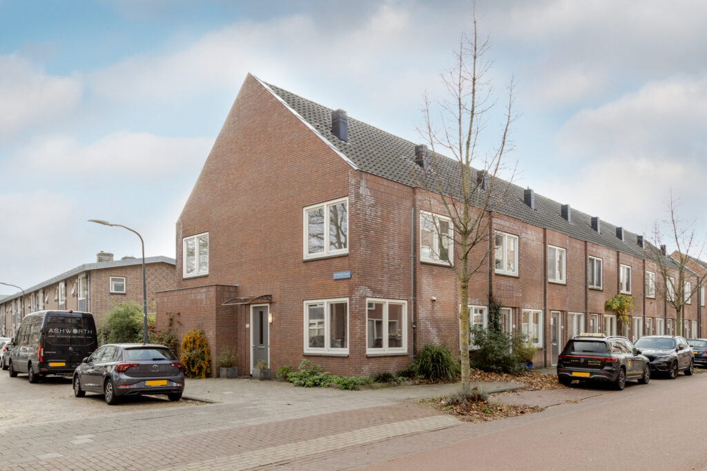 Brick residential buildings lined with parked cars.