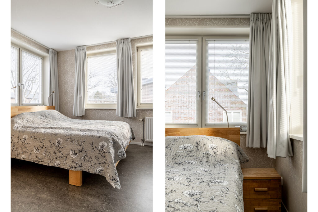 Cozy bedroom with floral bedspread and large windows.