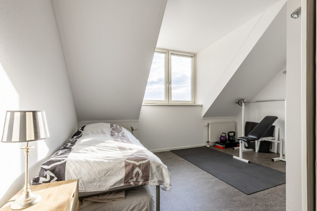 Attic room with bed and home gym equipment.