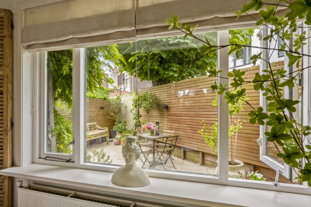 Cozy garden view through window with plants and statue.