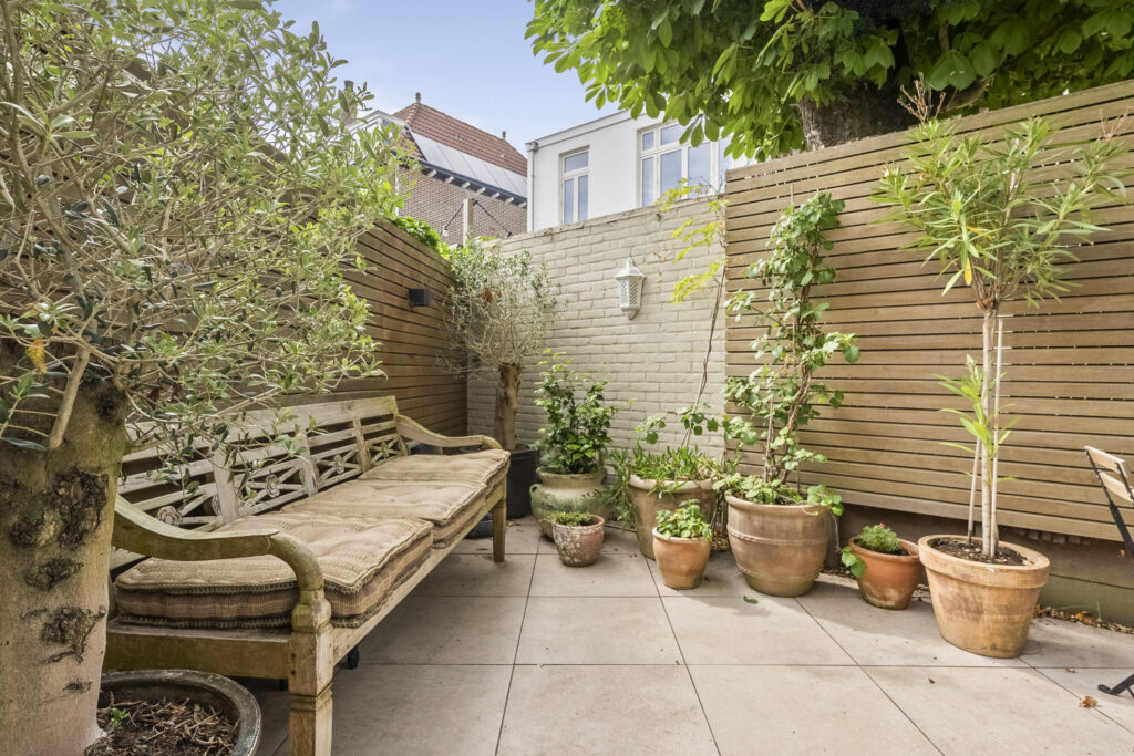 Cozy patio with wooden bench and potted plants.