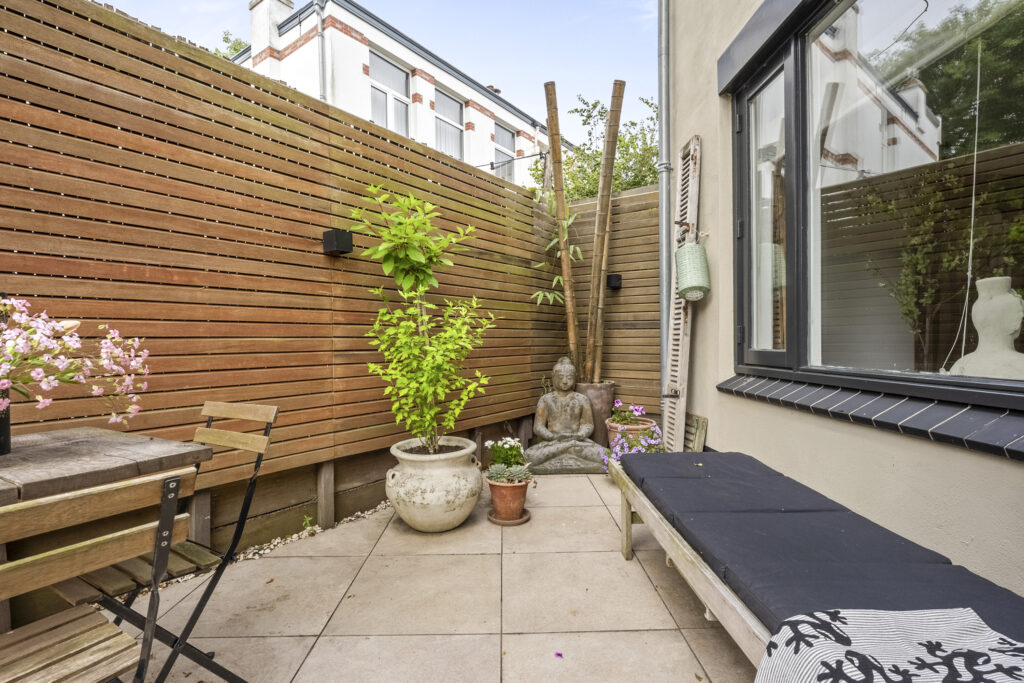Cozy patio with plants and wooden furniture.