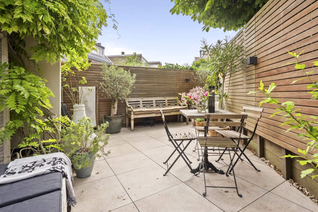 Cozy patio with plants and wooden furniture.