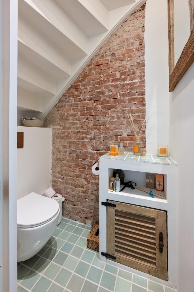 Compact bathroom with exposed brick and modern fixtures.