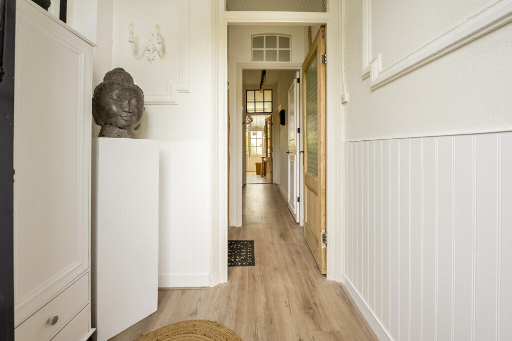 Cozy hallway with wooden door and Buddha sculpture.