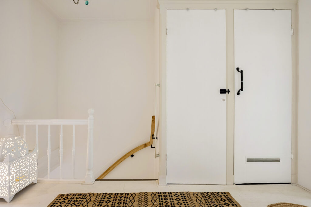White hallway with closed door and decorative lamp.