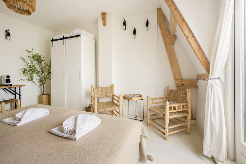 Cozy bedroom with wicker chairs and wardrobe.