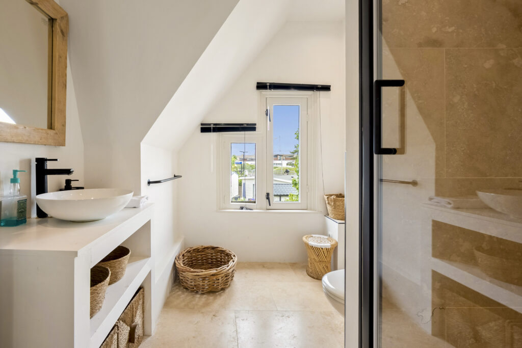 Modern bathroom with window and wicker baskets.