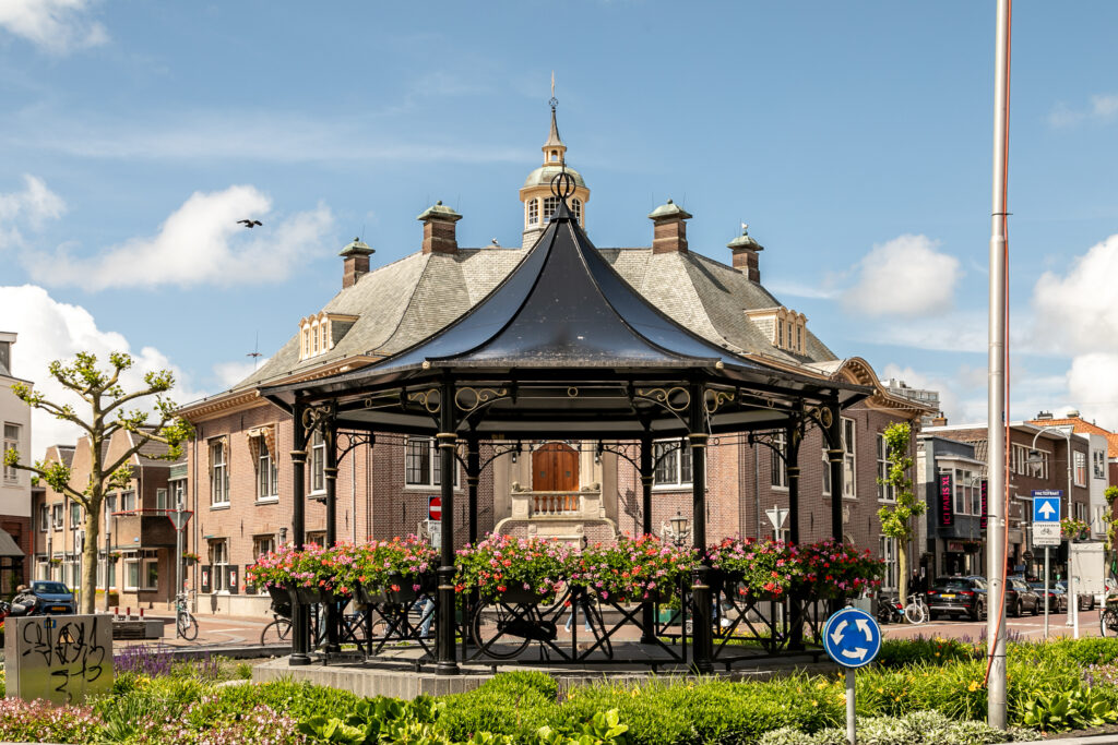Historic gazebo with flower arrangements and cloudy sky.