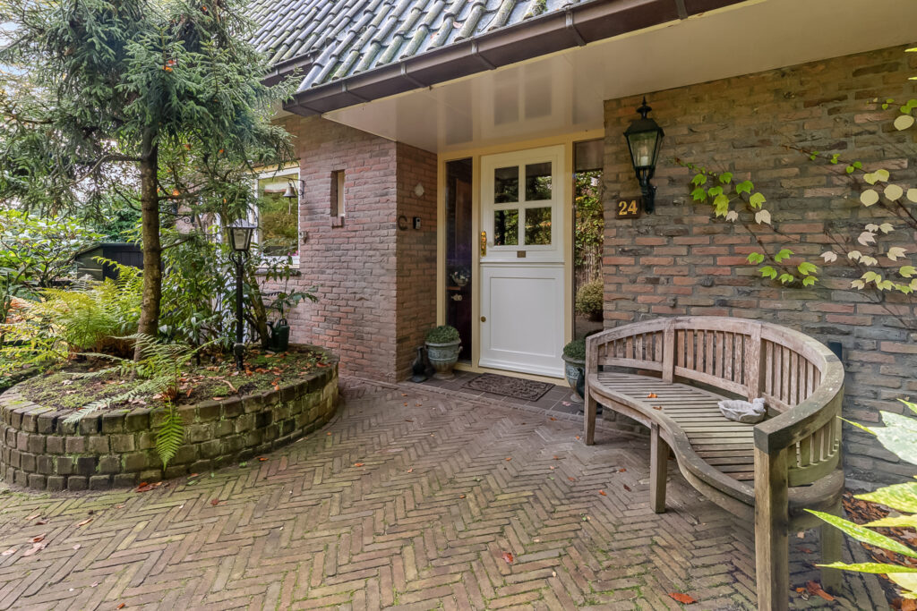 Charming brick house entrance with bench and plants.