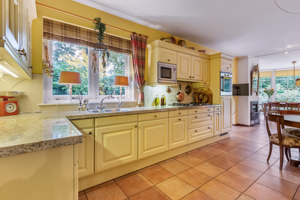 Spacious kitchen with yellow cabinets and dining area.