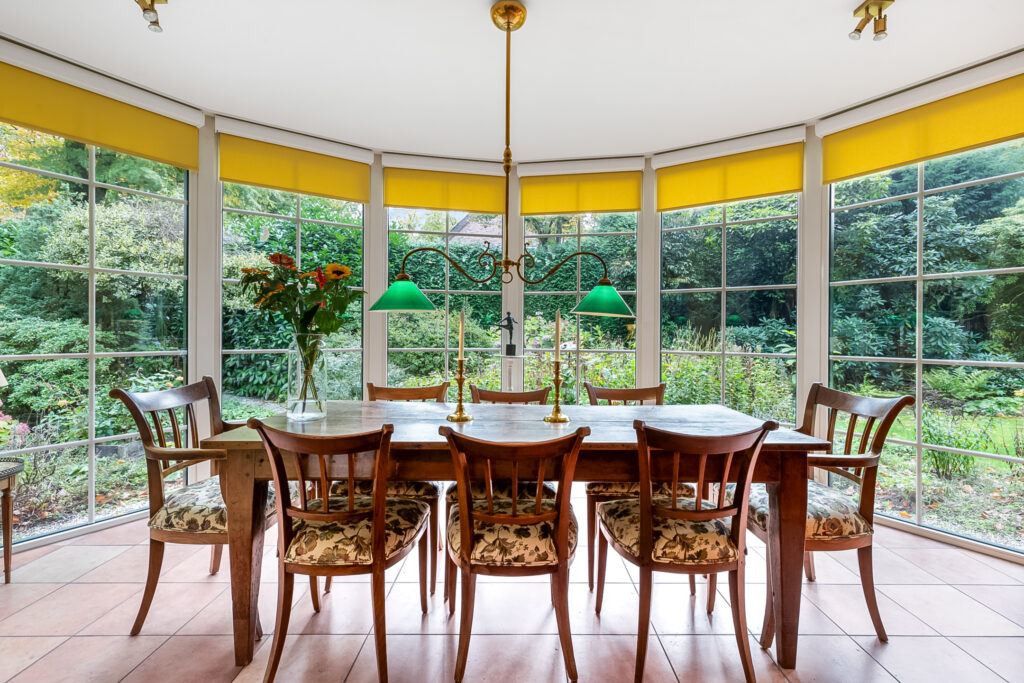 Dining room with garden view and wooden furniture.