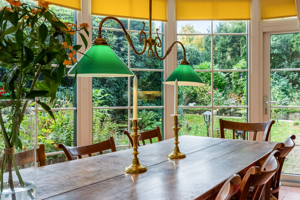 Dining room with garden view, green lamps, candlesticks.