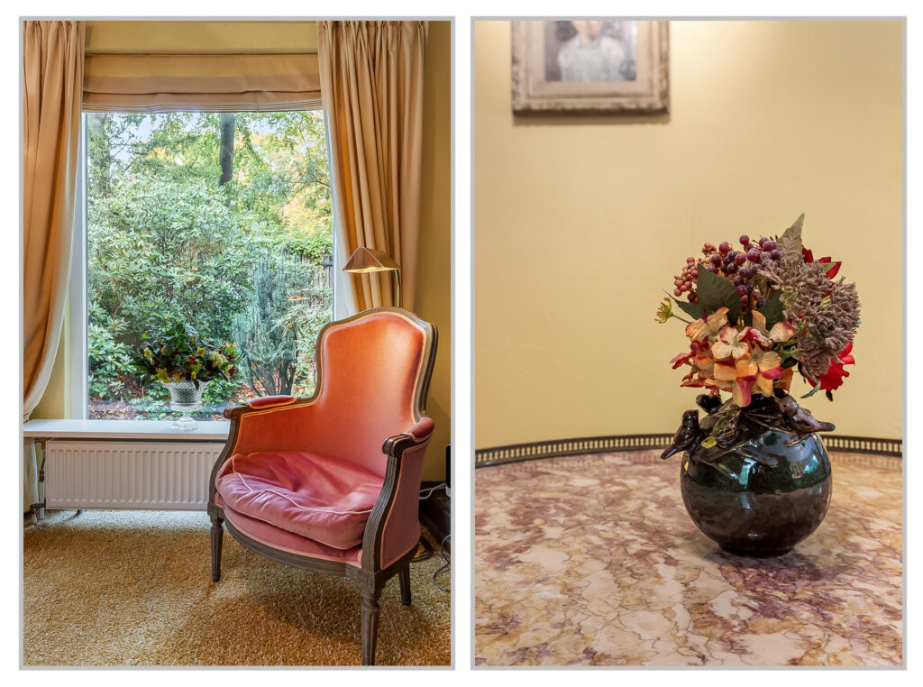 Cozy chair by window; vase with flowers on table.