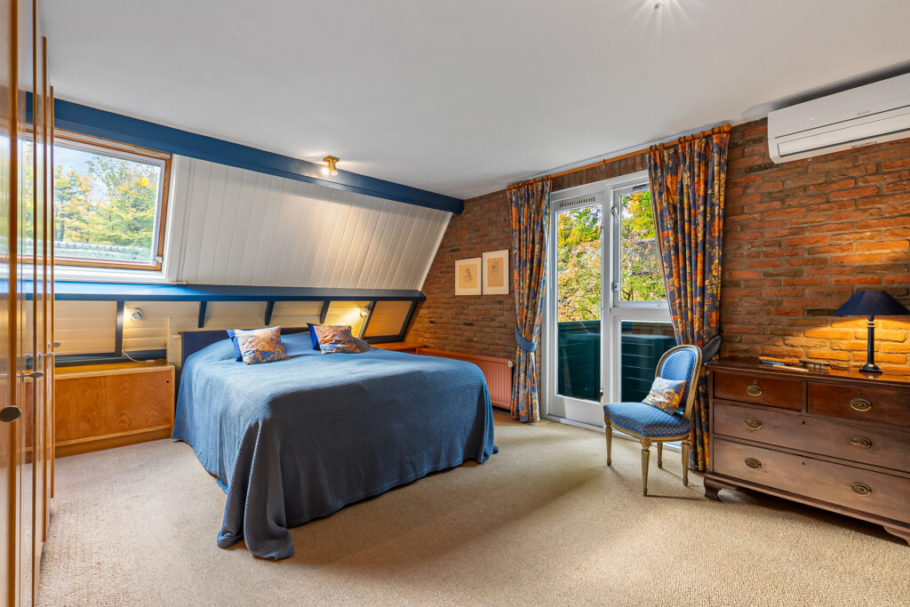Cozy bedroom with blue bedding and brick wall.