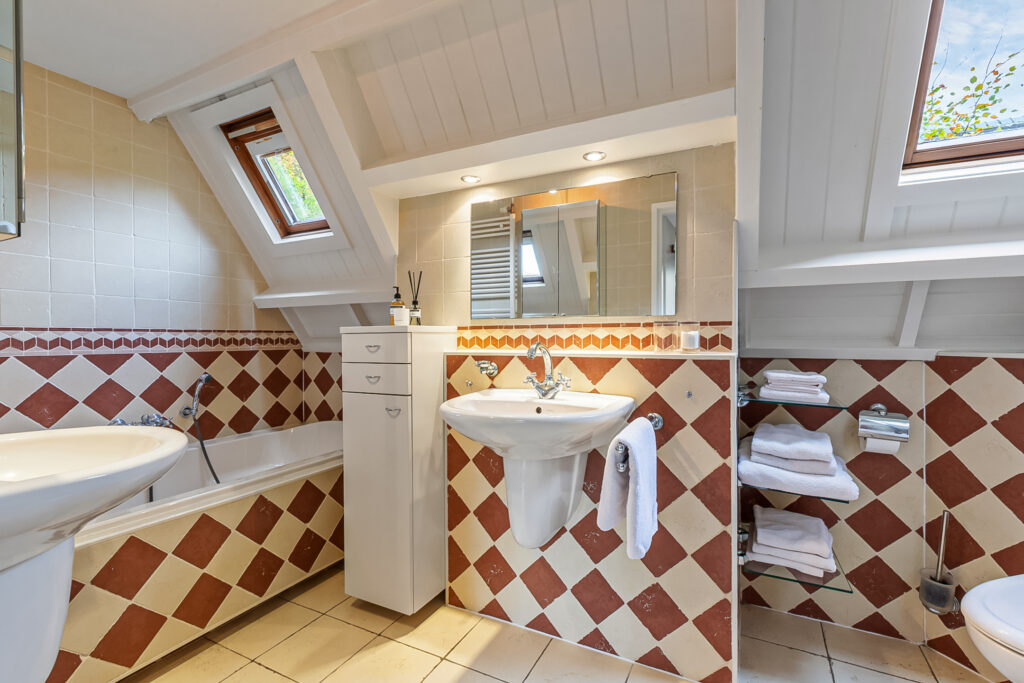Attic bathroom with skylights and tiled decor.