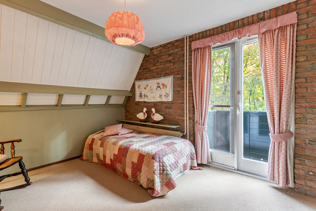 Cozy bedroom with colorful quilt and nature view.