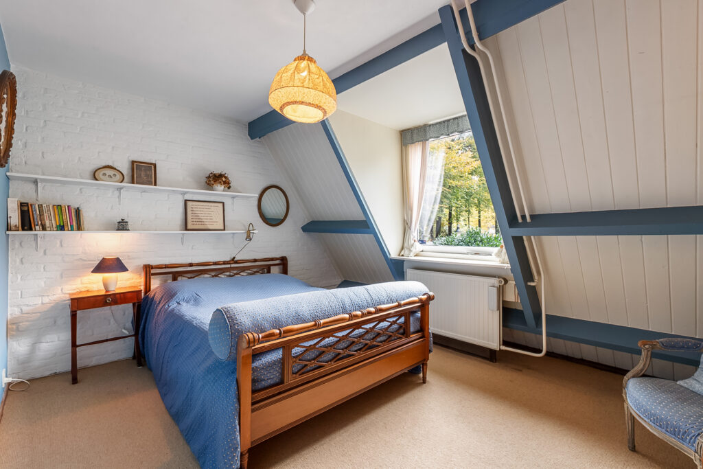 Cozy attic bedroom with blue decor and window view.