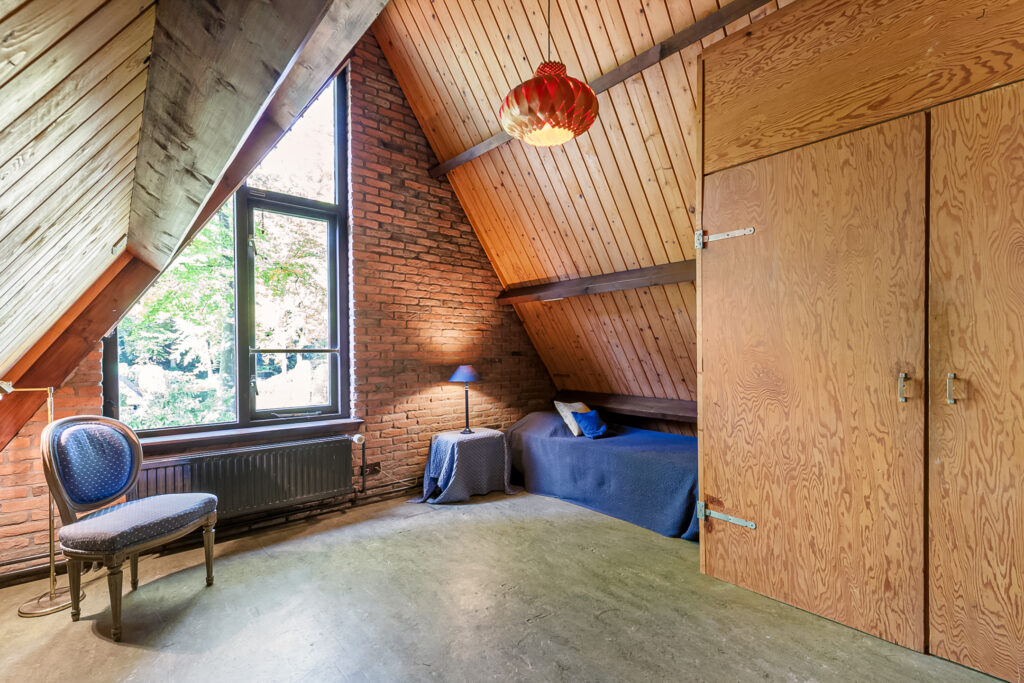 Cozy attic bedroom with wooden walls and furniture.