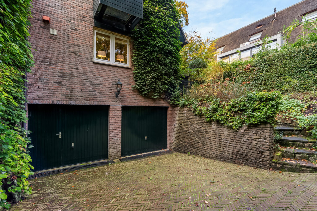 Brick garage with ivy-covered walls and greenery.