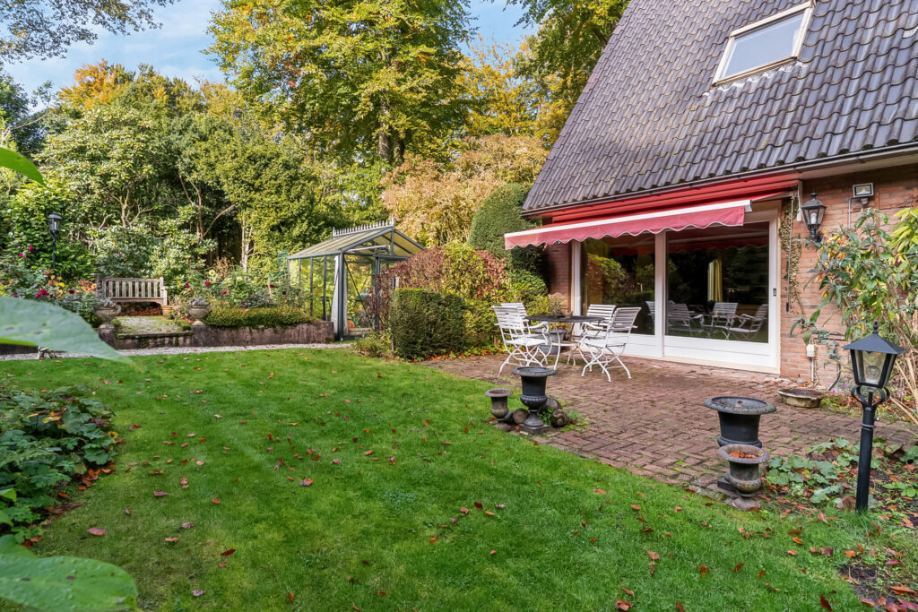 Charming garden with patio and greenhouse.