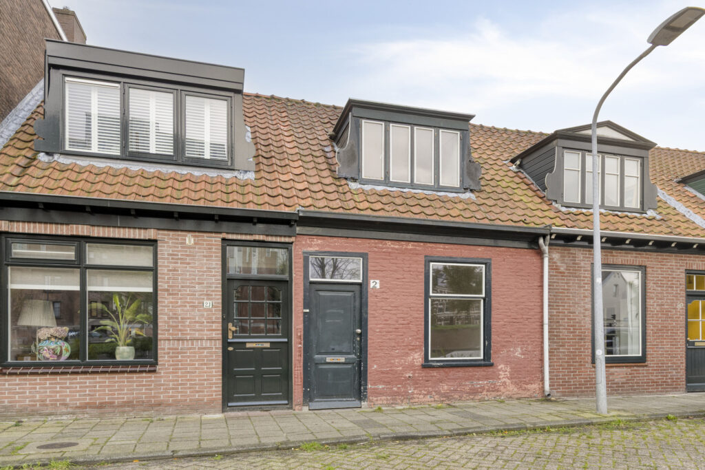 Charming brick house with dormer windows and street lamp.
