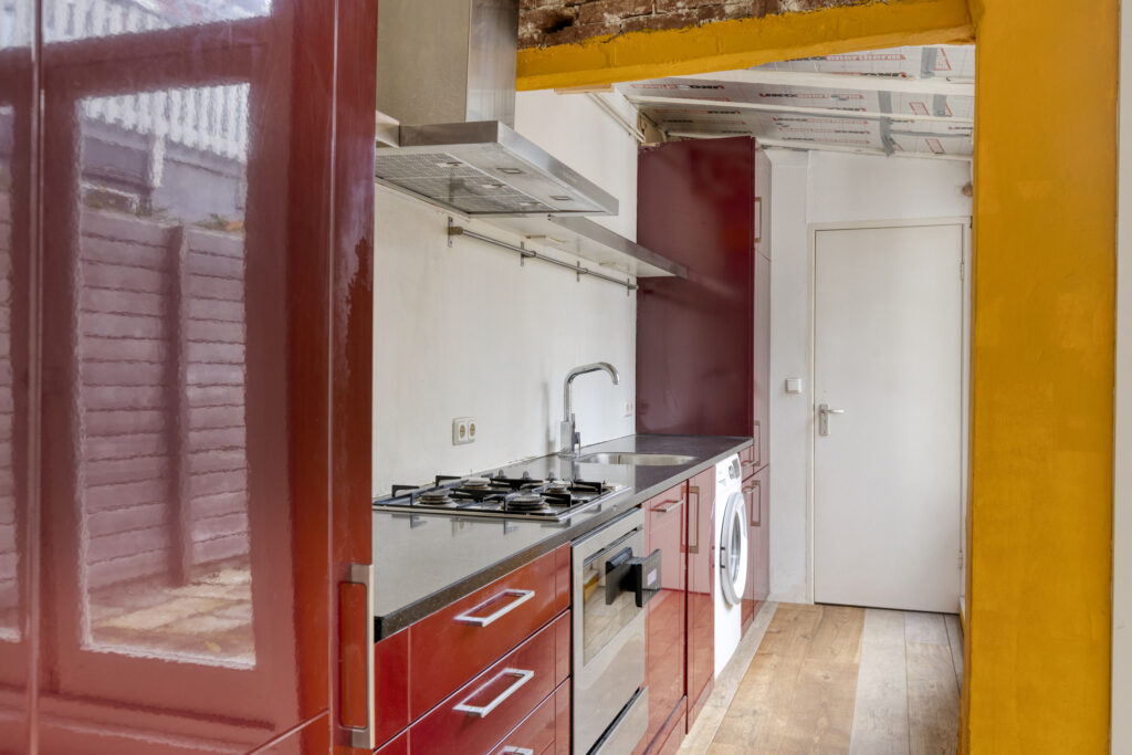 Compact modern kitchen with red cabinets and appliances.