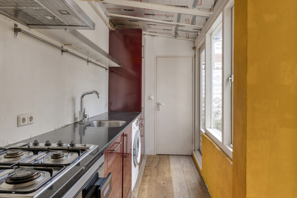 Narrow kitchen with stove, sink, and yellow walls.