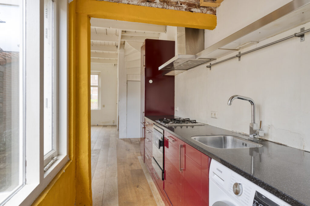 Modern kitchen with red cabinets and appliances.