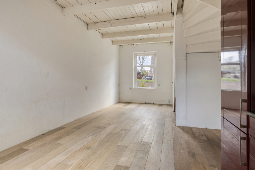 Empty room with wooden floor and window view.