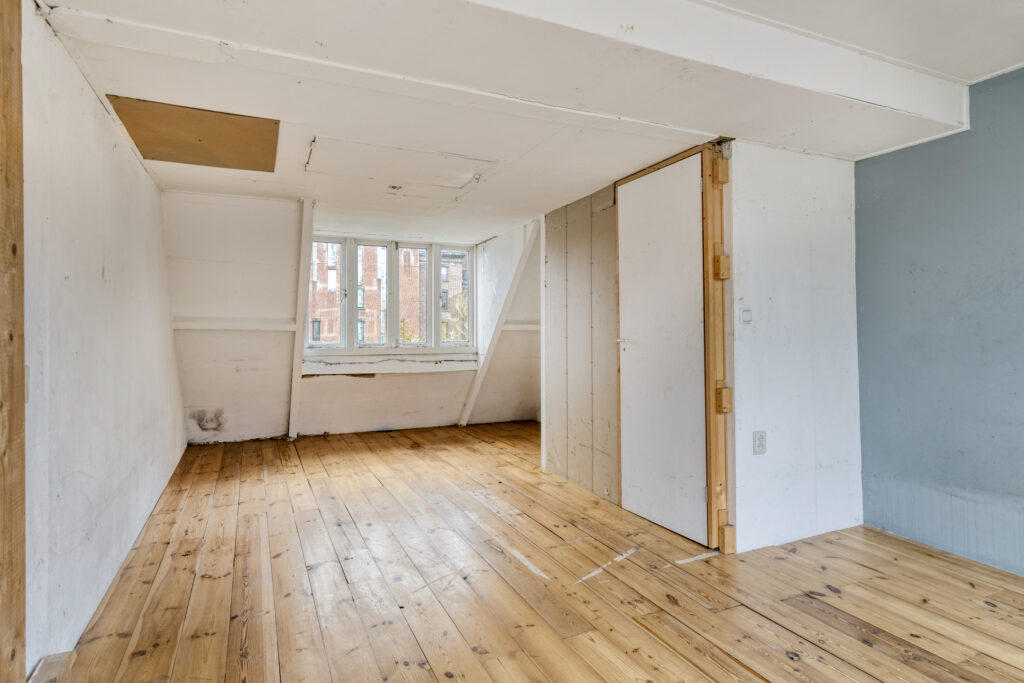 Empty attic room with wooden floor and window
