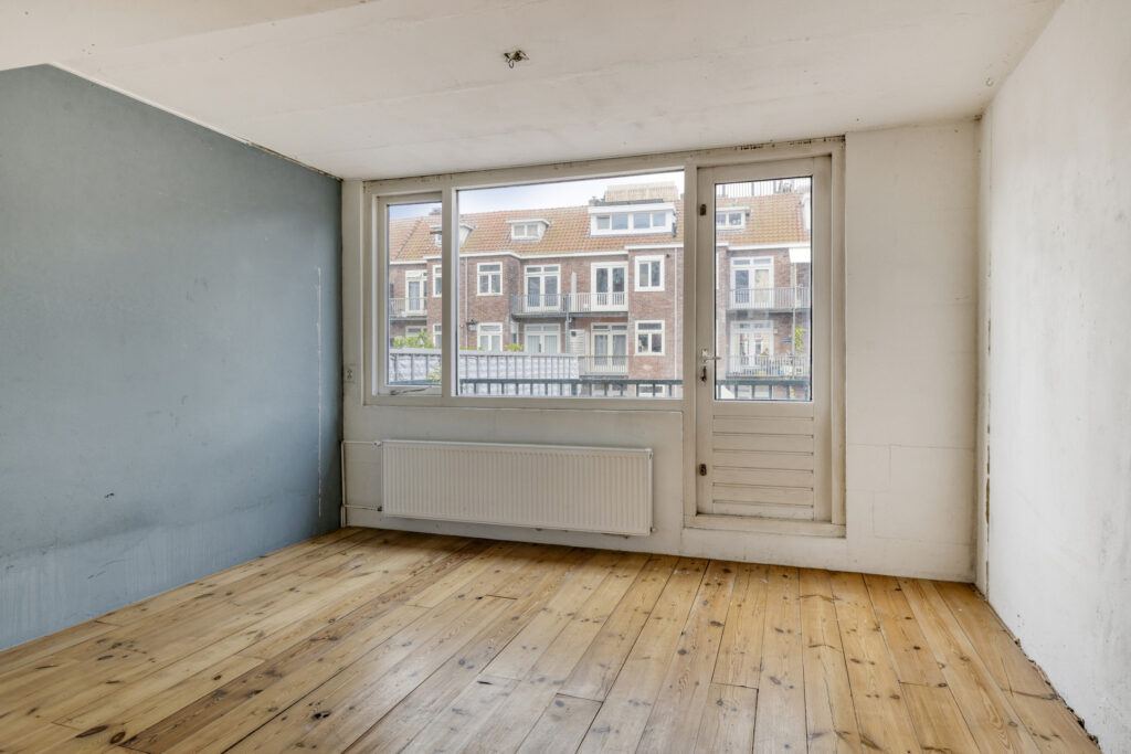 Empty room with wooden floor and large window.