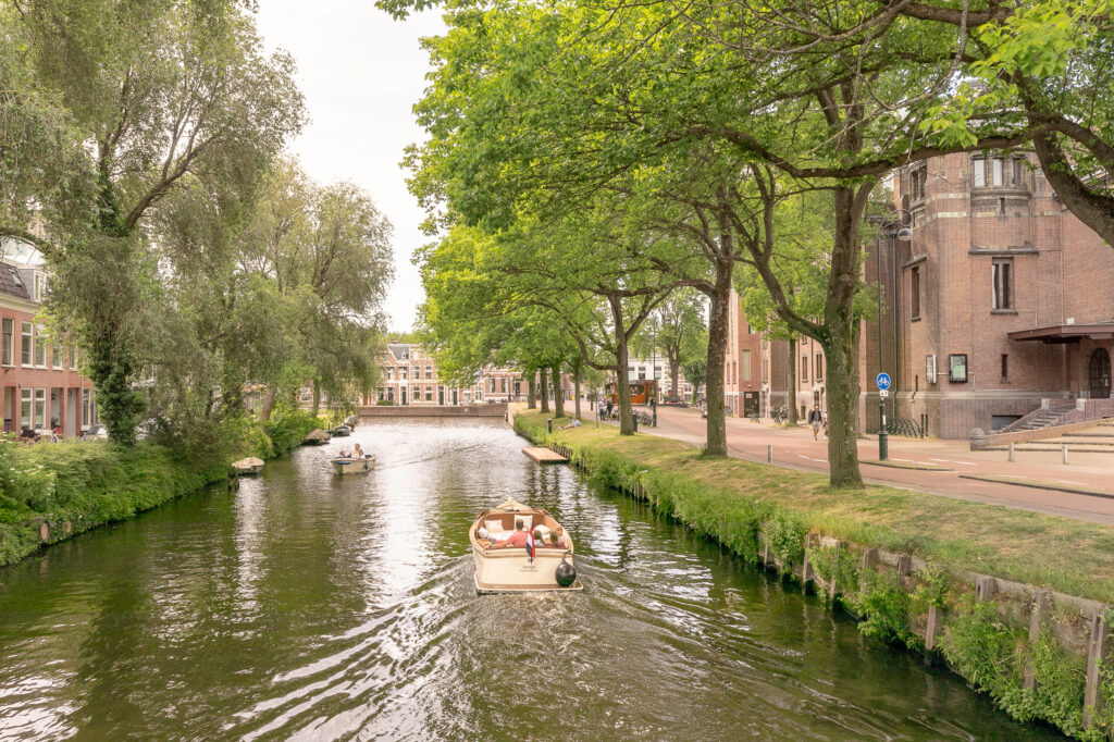Boat on scenic canal with trees and buildings.