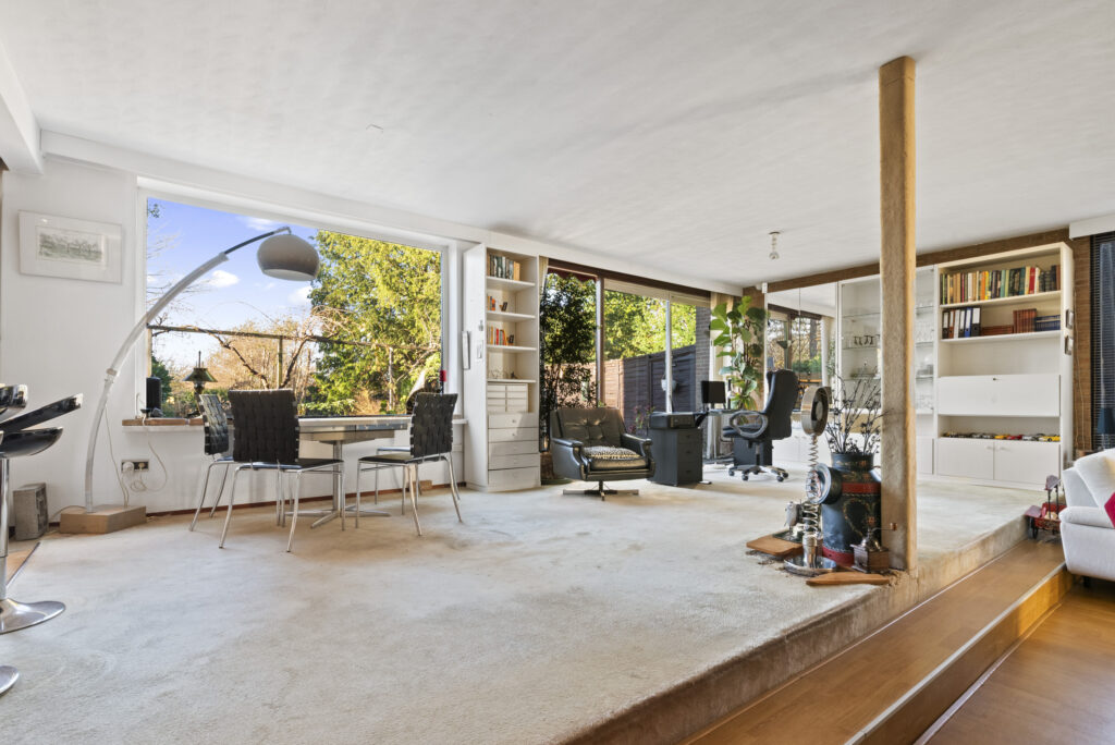 Spacious living room with large windows and bookshelves.